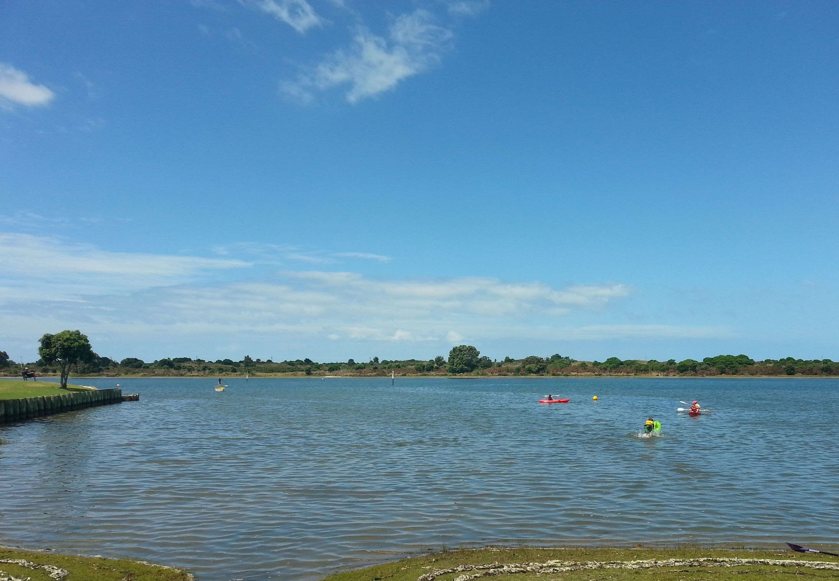 A calm lake with kayaks and a distant shoreline.