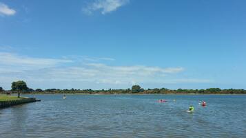 A calm lake with kayaks and a distant shoreline.