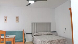 A bedroom with a bed, a chair, a desk, a ceiling fan, and two wall-mounted picture frames. - Two person apartment in ideal location (Conil de la Frontera)