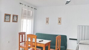 A room with a ceiling fan, a green sofa, a wooden table with chairs, and two framed pictures on the wall. - Two person apartment in ideal location (Conil de la Frontera)