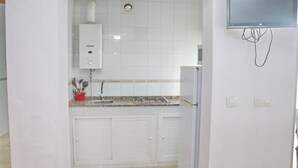 A compact kitchen with white cabinets, a built-in stove, and a microwave. - Two person apartment in ideal location (Conil de la Frontera)