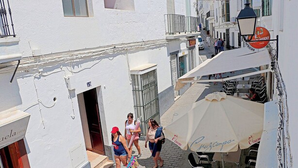 A narrow street with white buildings, a café with outdoor seating, and a sign for 'Capricho'. - Two person apartment in ideal location (Conil de la Frontera)