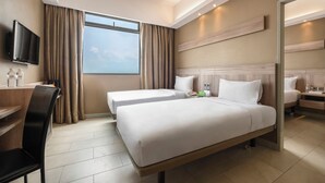 A hotel room with two beds, a desk, a chair, a TV, and a large window with curtains. - Cititel Express Penang (George Town)