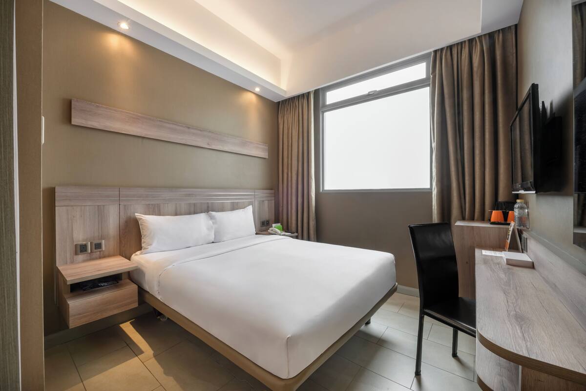 Une chambre d’hôtel moderne, dotée d’un grand lit, d’un bureau et d’une télévision.