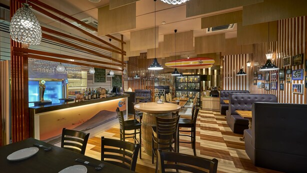 A restaurant interior with wooden furniture, a bar area, and hanging pendant lights. - Cititel Express Penang (George Town)