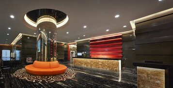 Un vestíbulo moderno con una columna central, un mostrador de recepción y una alfombra estampada.