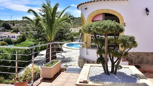 Area piscina con vista aperta sul paesaggio circostante, inclusa una palma e un edificio con un arco giallo.