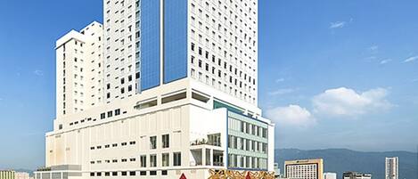 A high-rise hotel with a distinctive curved top, multiple floors, and a prominent entrance with a golden decorative facade.