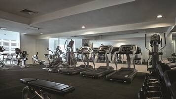 Un gimnasio con cintas de correr, elípticas y bancos de pesas.
