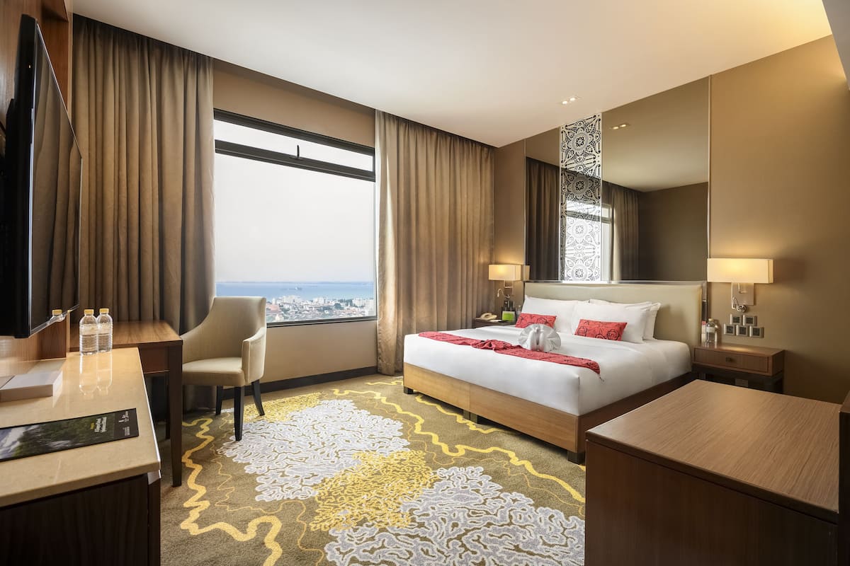 Een hotelkamer met een groot bed, een bureau, een stoel, een televisie en uitzicht op de stad.