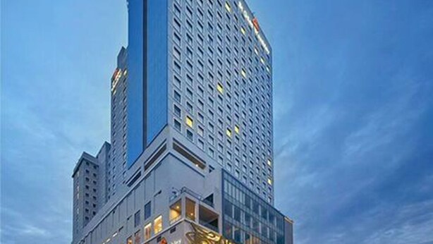 Een modern hoog hotel met een kenmerkend gebogen dak en meerdere verdiepingen.