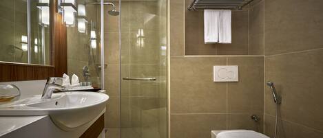 Une salle de bain moderne avec une douche à parois de verre, un lavabo avec un miroir et des toilettes.