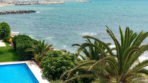 Vista costeira com piscina, vegetação exuberante e um paredão rochoso.