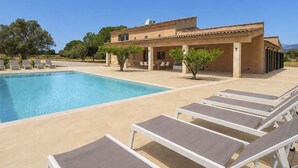 A poolside area with lounge chairs, a swimming pool, and a building with a tiled roof. - Wonderful private villa for 12 people with A/C, private pool, WIFI, TV, patio and panoramic view (Costitx)