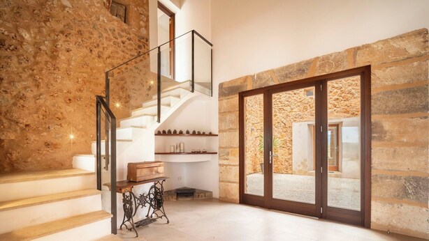 A staircase with a stone wall, a wooden bench, and a view of an outdoor area through glass doors. - Wonderful private villa for 12 people with A/C, private pool, WIFI, TV, patio and panoramic view (Costitx)