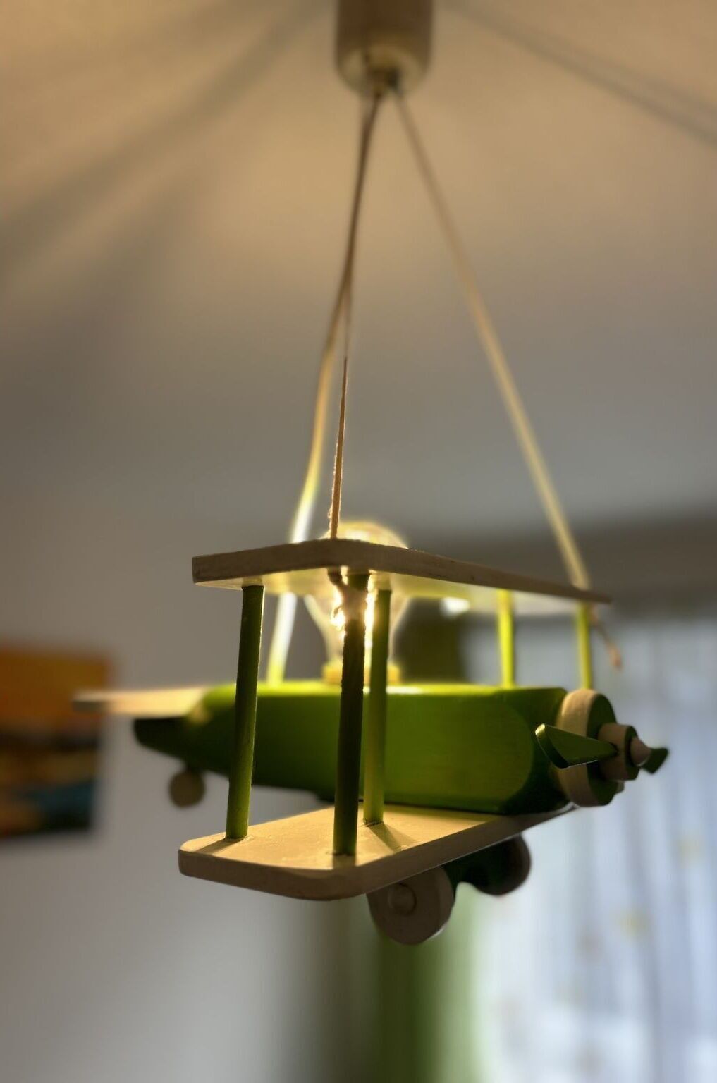 Une maquette d’avion suspendue, avec un fuselage vert et une hélice blanche.