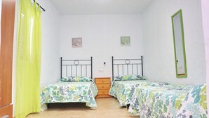 Una habitación con dos camas, un aparador de madera, un espejo y dos cuadros pequeños.