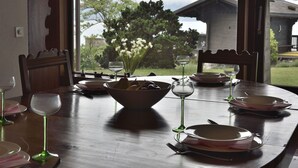 A dining table set with plates, bowls, and wine glasses, overlooking a mountainous landscape with a bird flying in the sky.