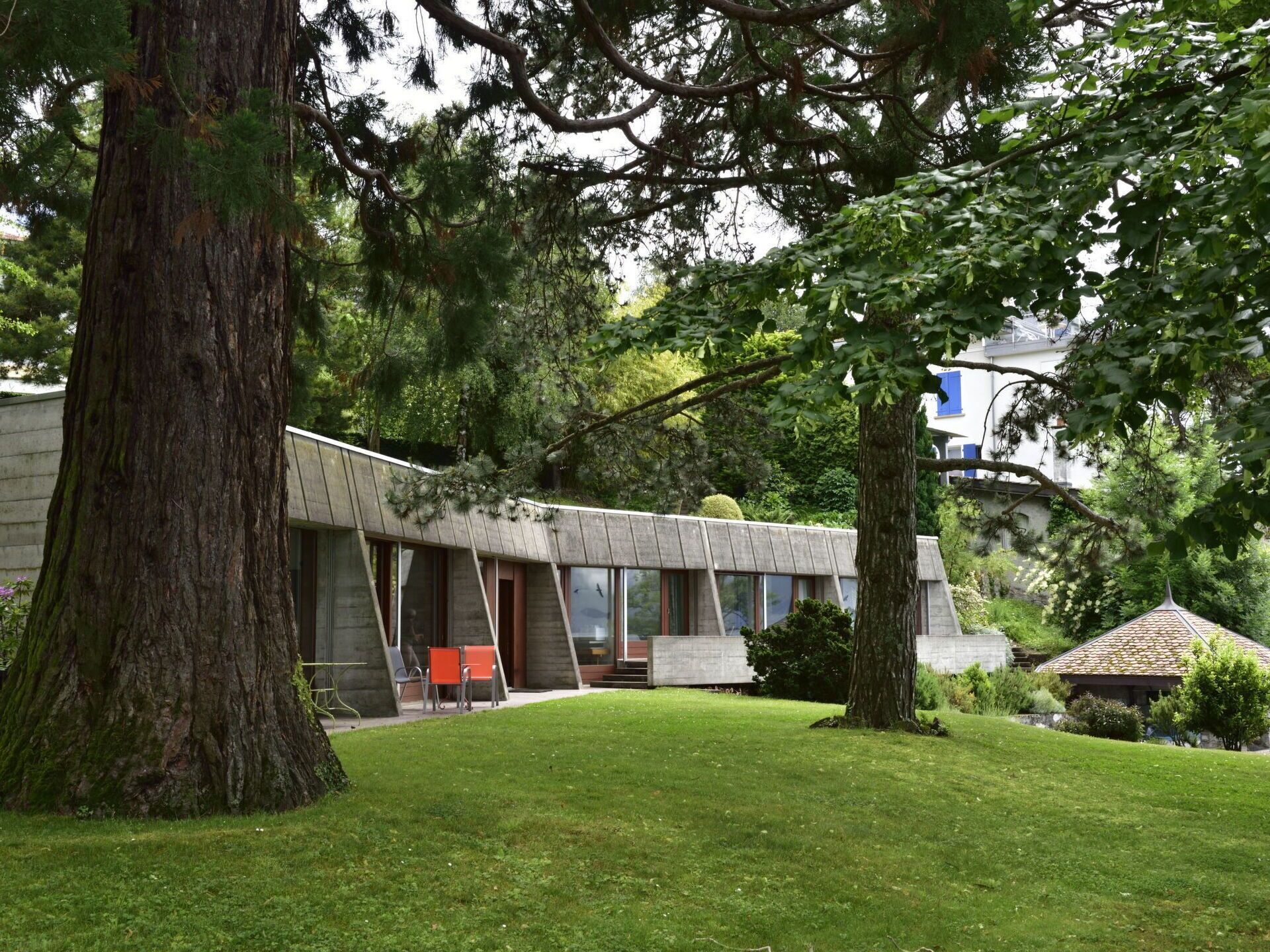 Un bâtiment moderne doté d’un toit incurvé, de grandes fenêtres et d’une cour verdoyante.