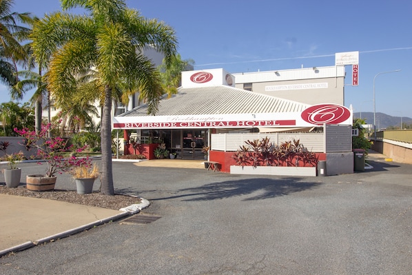 The Riverside Central Hotel with a prominent red and white sign, a parking lot, and surrounding palm trees.