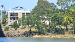 A motel with a signboard, located near a body of water with trees and a grassy area. - Rockhampton Riverside Central Hotel (Rockhampton)