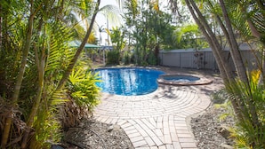 A backyard with a circular brick pool surrounded by palm trees and a brick patio. - Rockhampton Riverside Central Hotel (Rockhampton)
