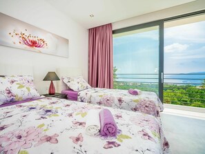 Quarto com duas camas, uma janela grande e vista para o mar.