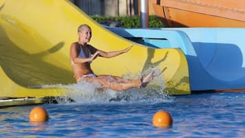 Eine Person rutscht auf einer Wasserrutsche in ein Schwimmbecken.