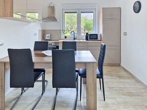 A modern kitchen with a dining table, chairs, a microwave, and a refrigerator.