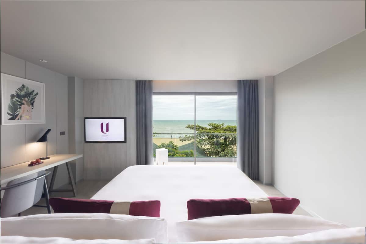 Una habitación de hotel con una cama grande, un escritorio y vistas a la playa.