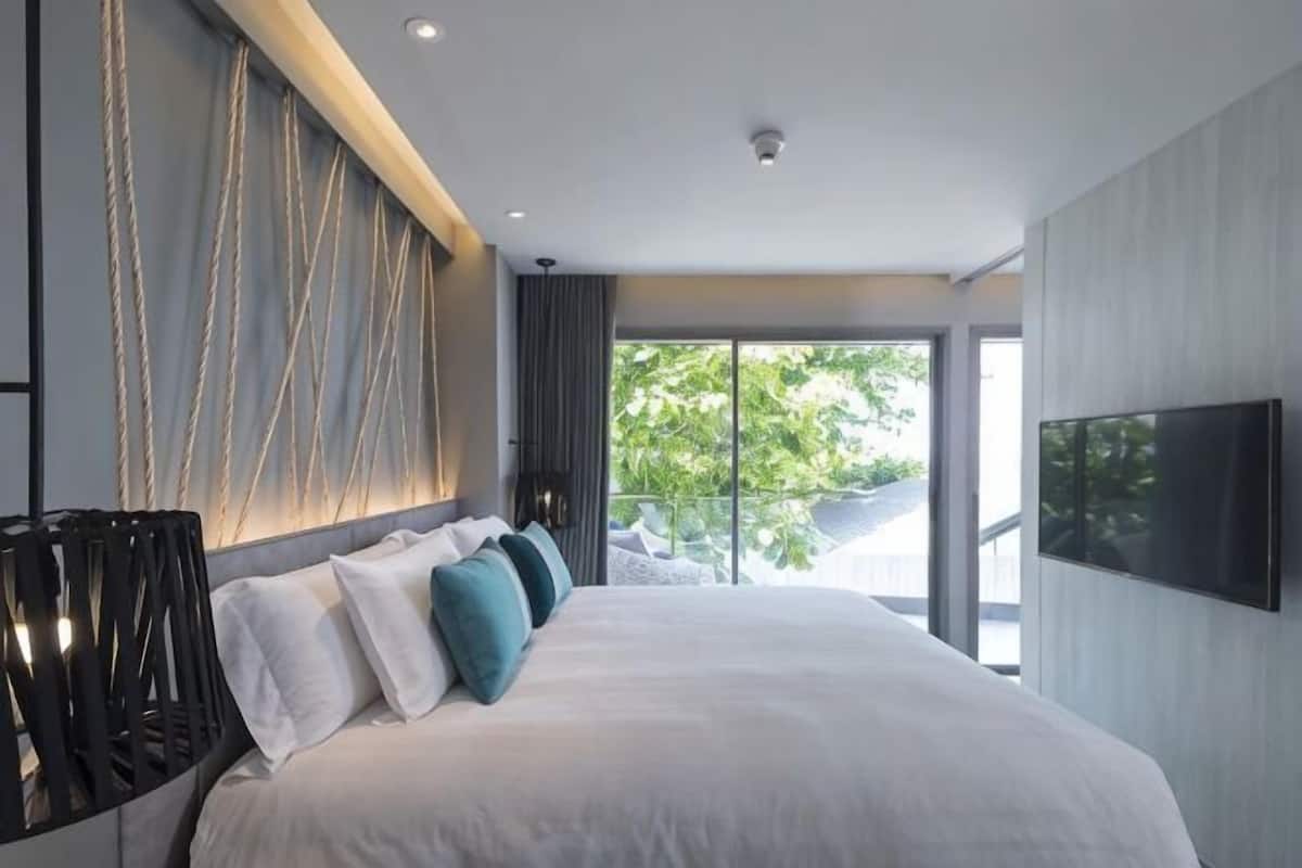 Una habitación de hotel moderna con una cama grande, un televisor de pantalla plana y vistas al exterior.