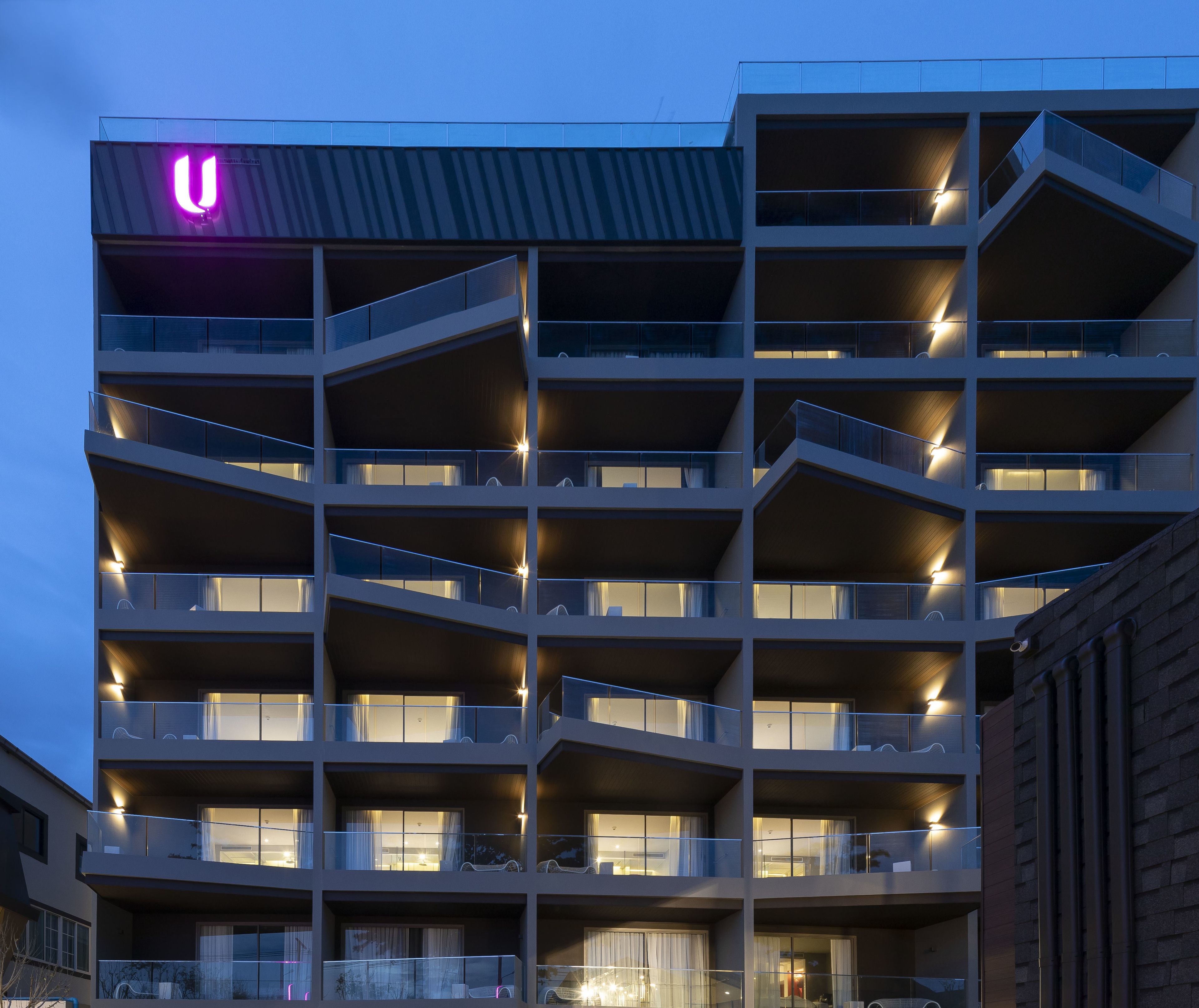 A multi-story building with balconies, a prominent 'U' sign, and a modern architectural design.