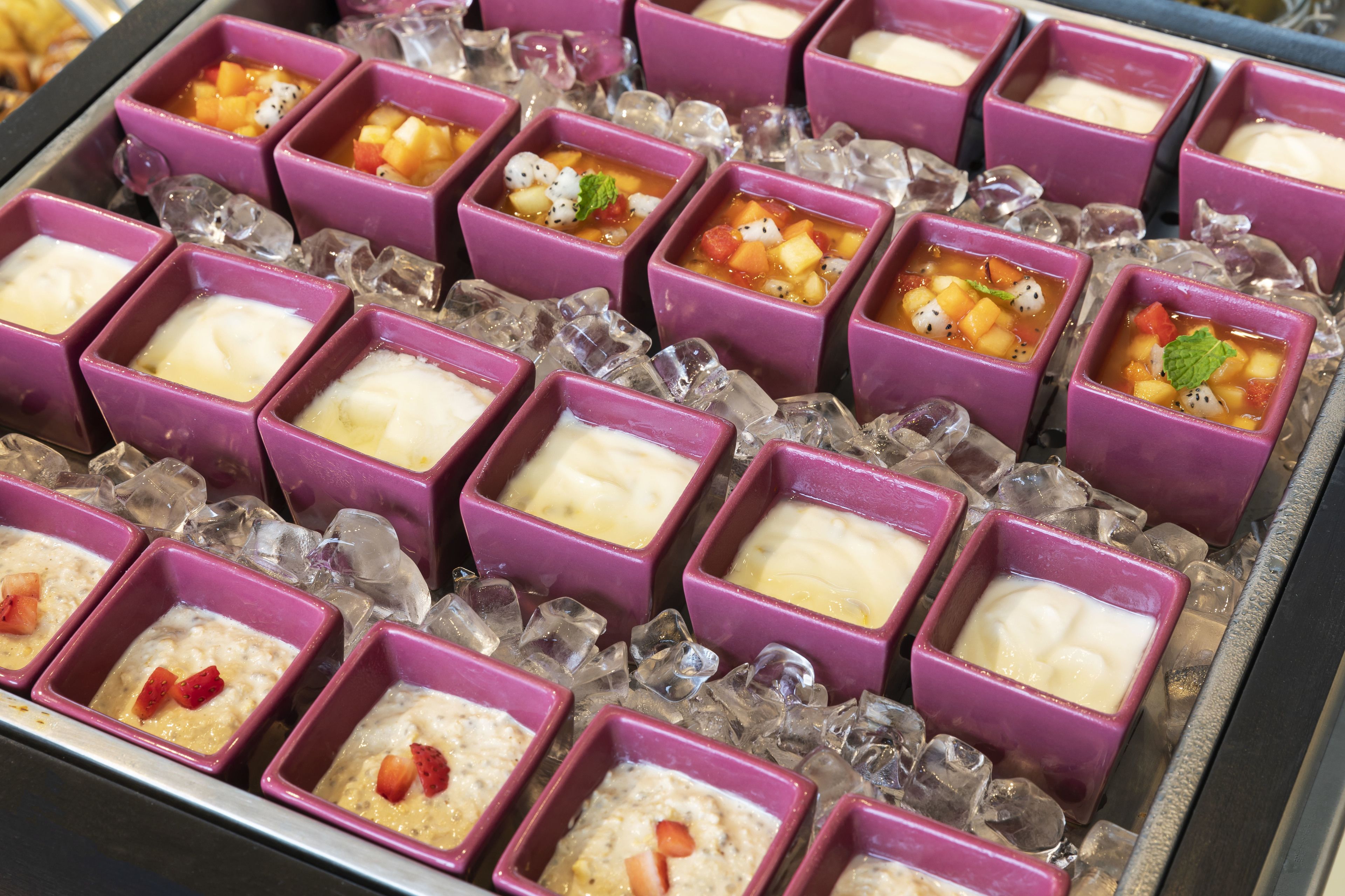 A dessert display with various ice cream flavors in purple containers.