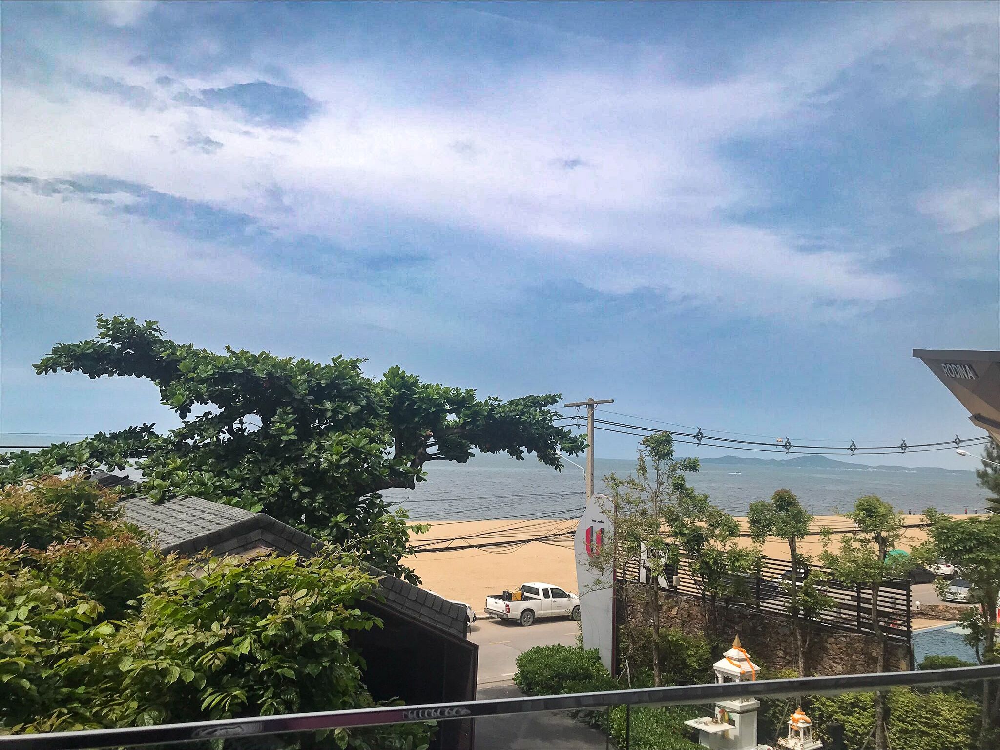 Blick auf die Küste mit Strand, einem geparkten Lastwagen und einem tempelähnlichen Gebäude.