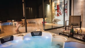 A hot tub area with a glass partition, a bar with drinks, and a view of a pool and outdoor seating. - Suites d'hôtes Prestige Mas de l'étoile (Saint-Laurent-d'Aigouze)