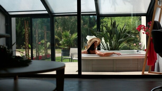 A room with a large glass window, a bathtub, and a table. - Suites d'hôtes Prestige Mas de l'étoile (Saint-Laurent-d'Aigouze)