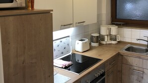 A modern kitchen with wooden cabinets, a built-in oven, a microwave, a toaster, and a coffee maker. - Haus Dippold (Reit im Winkl)