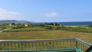 Um campo gramado com um edifício e vista para o mar.