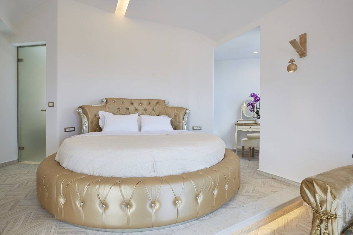 A large, round bed with a tufted headboard in a modern hotel room.