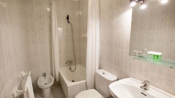 Un baño con bañera, inodoro, bidé y lavamanos.