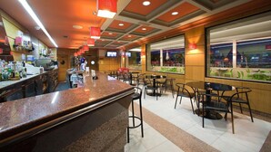 A restaurant with a bar area, multiple tables and chairs, and a large window offering a view of the outside. - Hostal Terra Chá (Villalba)