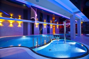 Una piscina interior moderna con diseño curvo, rodeada de paredes con luces empotradas.