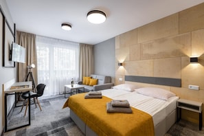 Una habitación de hotel moderna con una cama, un escritorio, una silla, un sofá y un televisor.