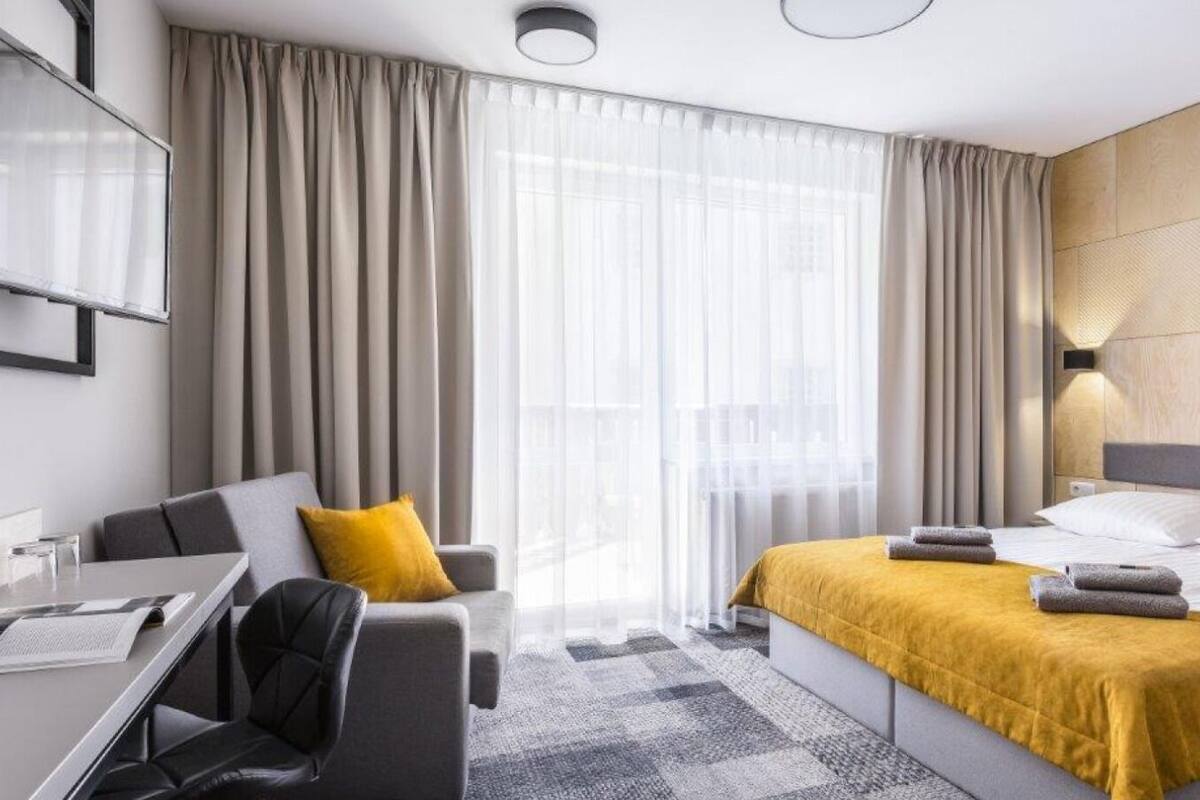 Een moderne hotelkamer met een bed, een bureau, een stoel en een bank.