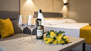 A hotel room with a bed, a table with two wine glasses and a bottle of wine, and a bouquet of yellow roses. - KRISTINA Willa & Spa (Szklarska Poreba)