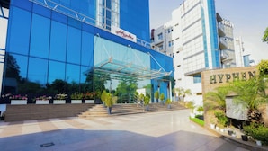 A modern building with a glass facade and the name "Hyphen" on the entrance. - Hyphen Business Hotel (Noida)