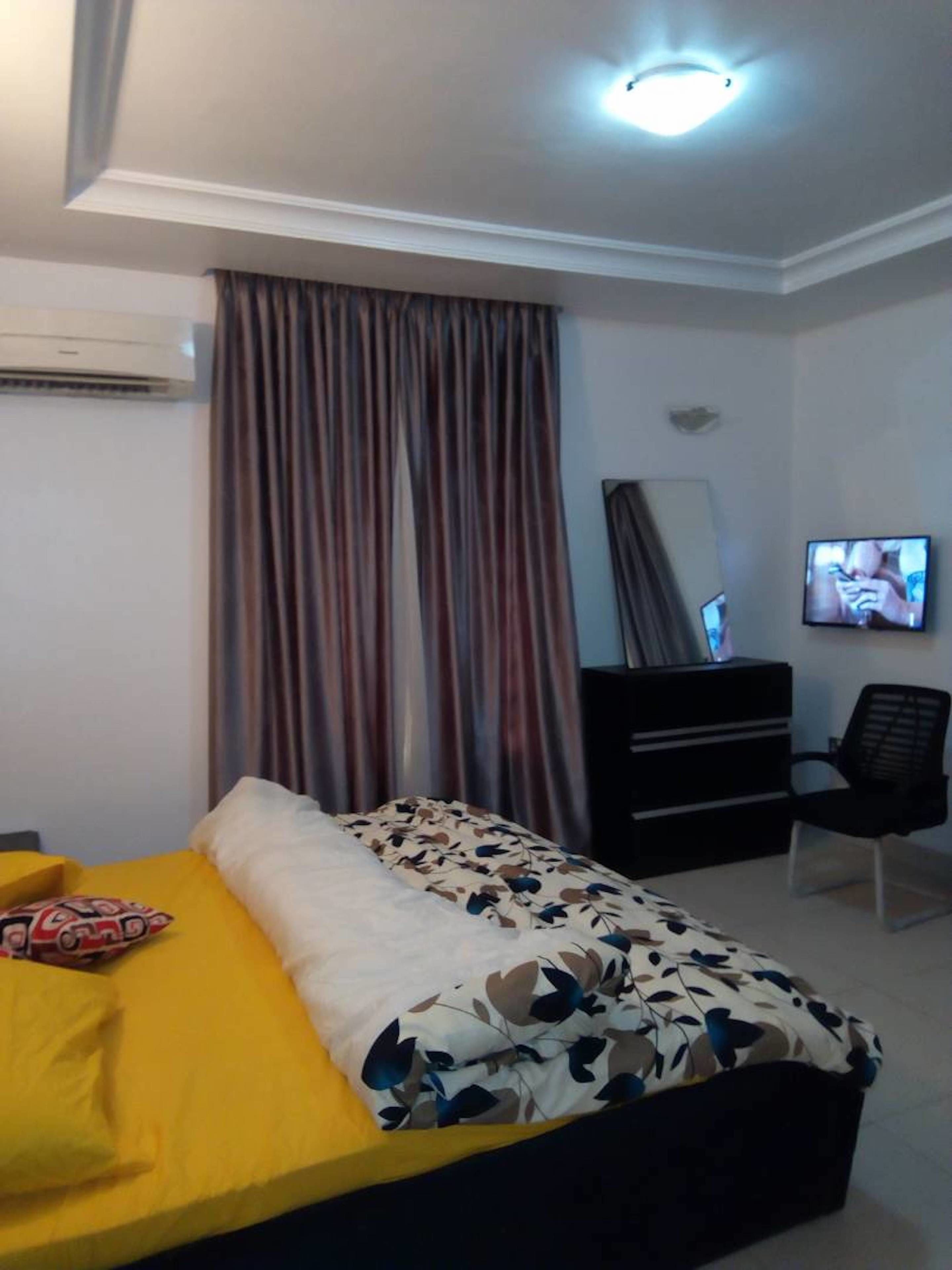 Een hotelkamer met een bed, een televisie, een dressoir en een stoel.
