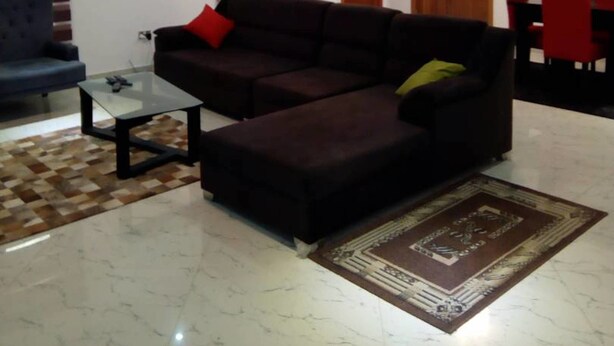 A modern living room with a sectional sofa, a glass coffee table, and a patterned rug. - Reeve Court Apartment (Lagos)