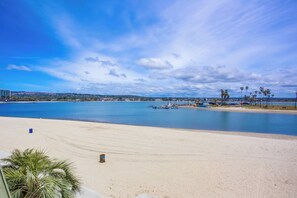 A beach with a clear sky, calm water, and distant buildings.
