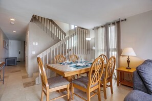 A dining area with a wooden table and chairs, a staircase, and a lamp on a side table.
